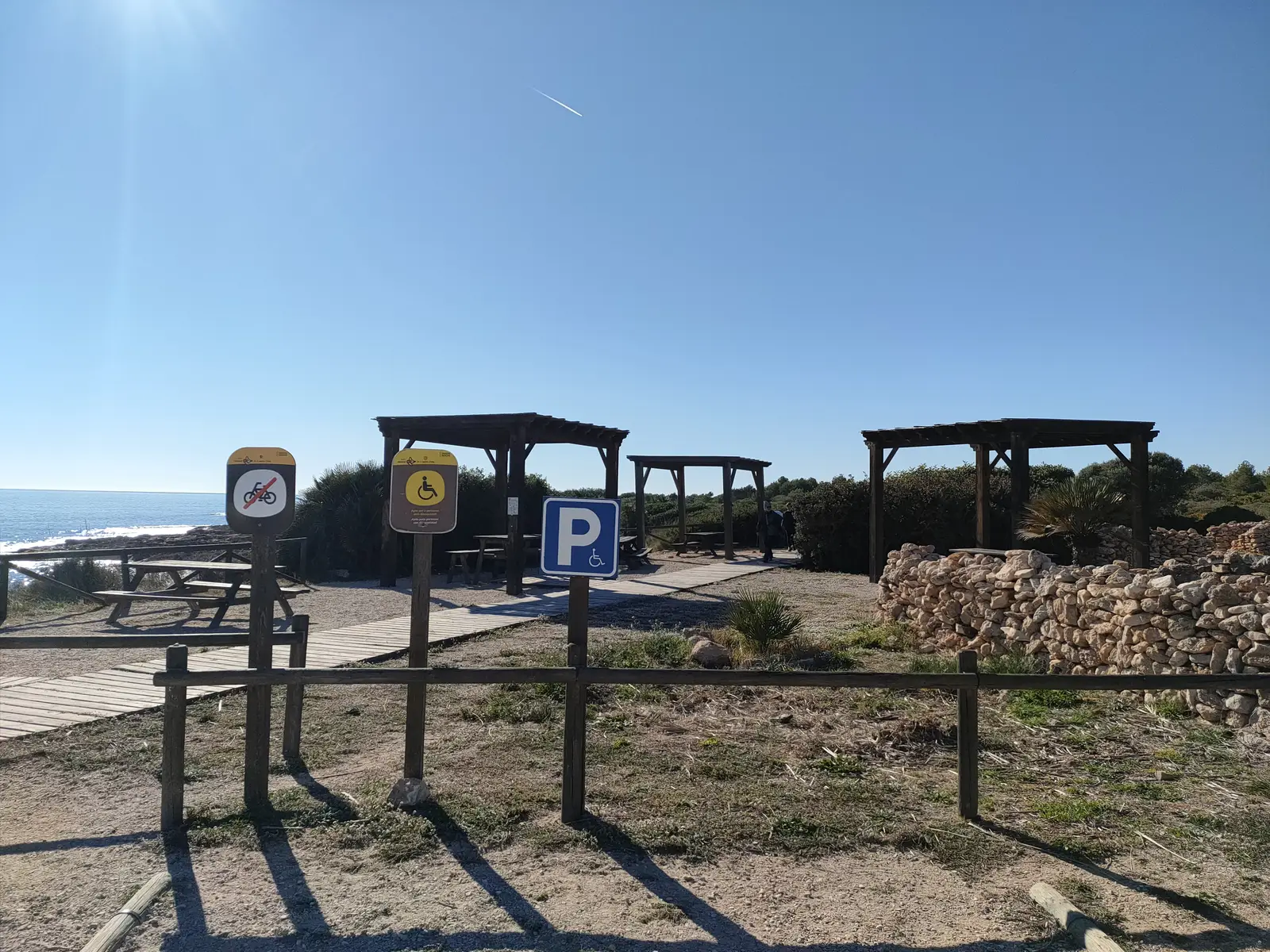 Zona de aparcamiento con señales de parking y de bicicletas junto a la costa de la Sierra de Irta