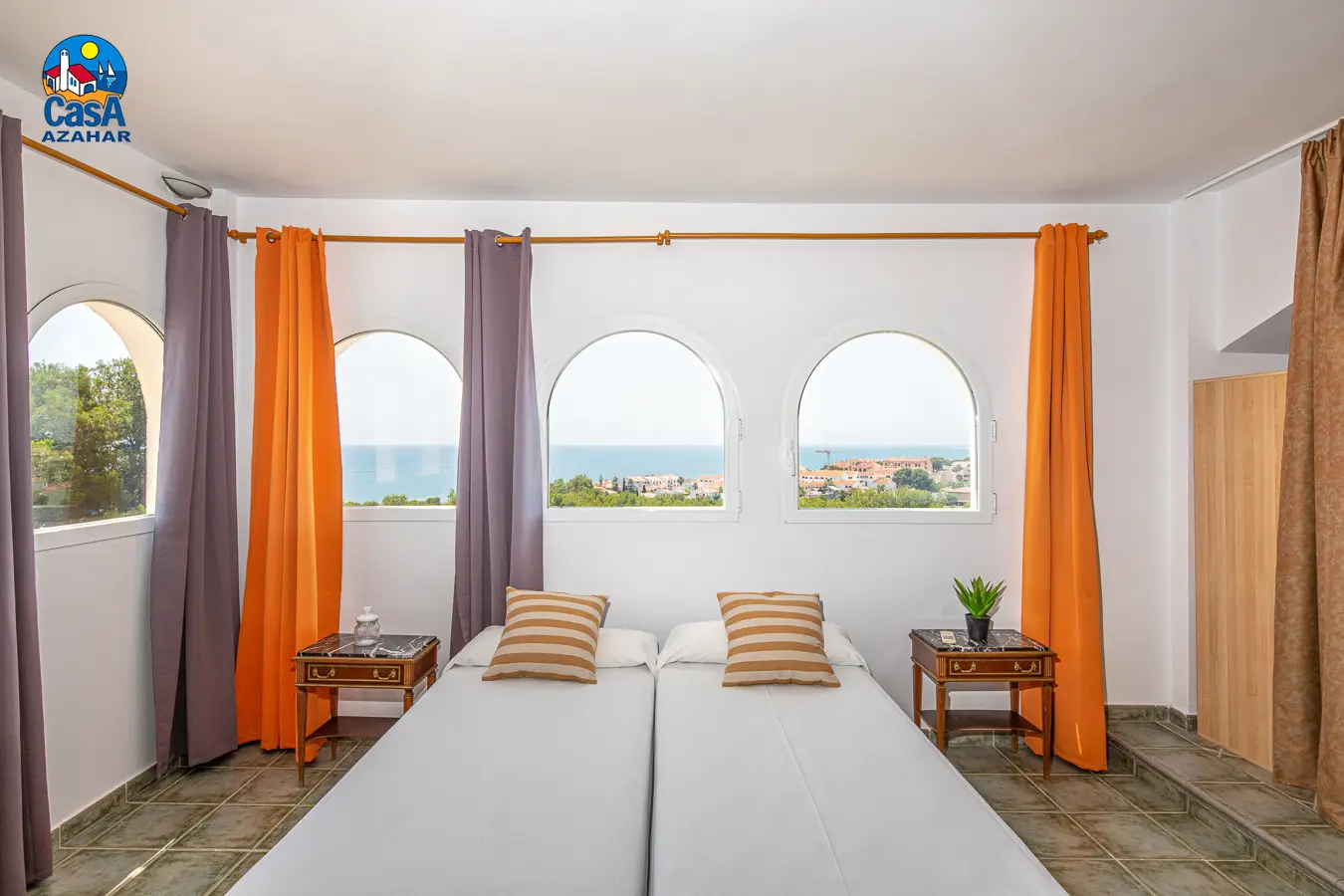 Schlafzimmer einer Ferienwohnung im Marcomar mit Bogenfenstern und Meerblick